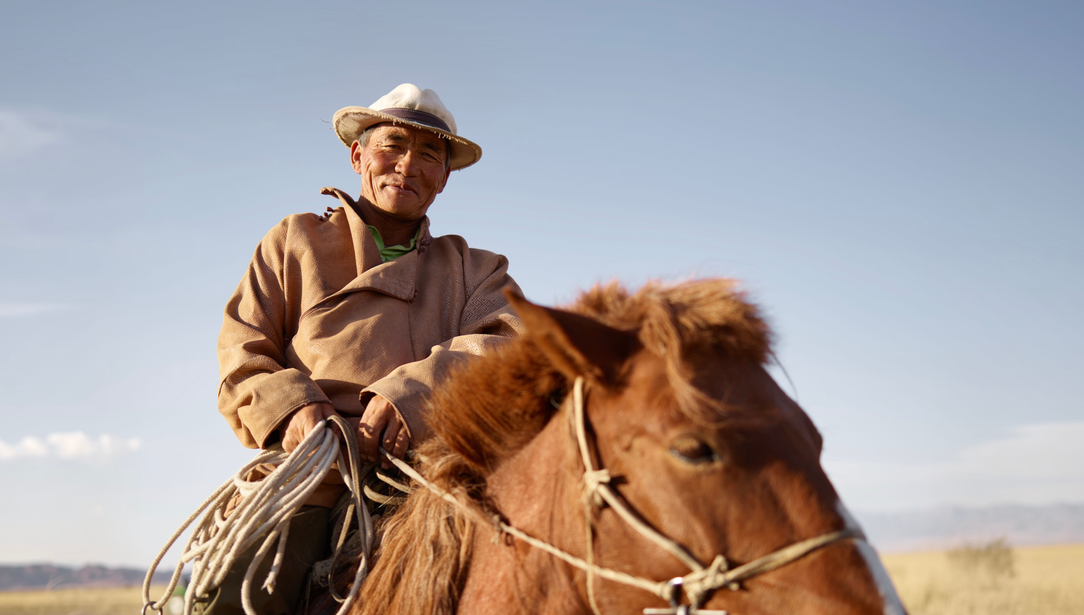 A Mongolian herder on horseback on the steppe